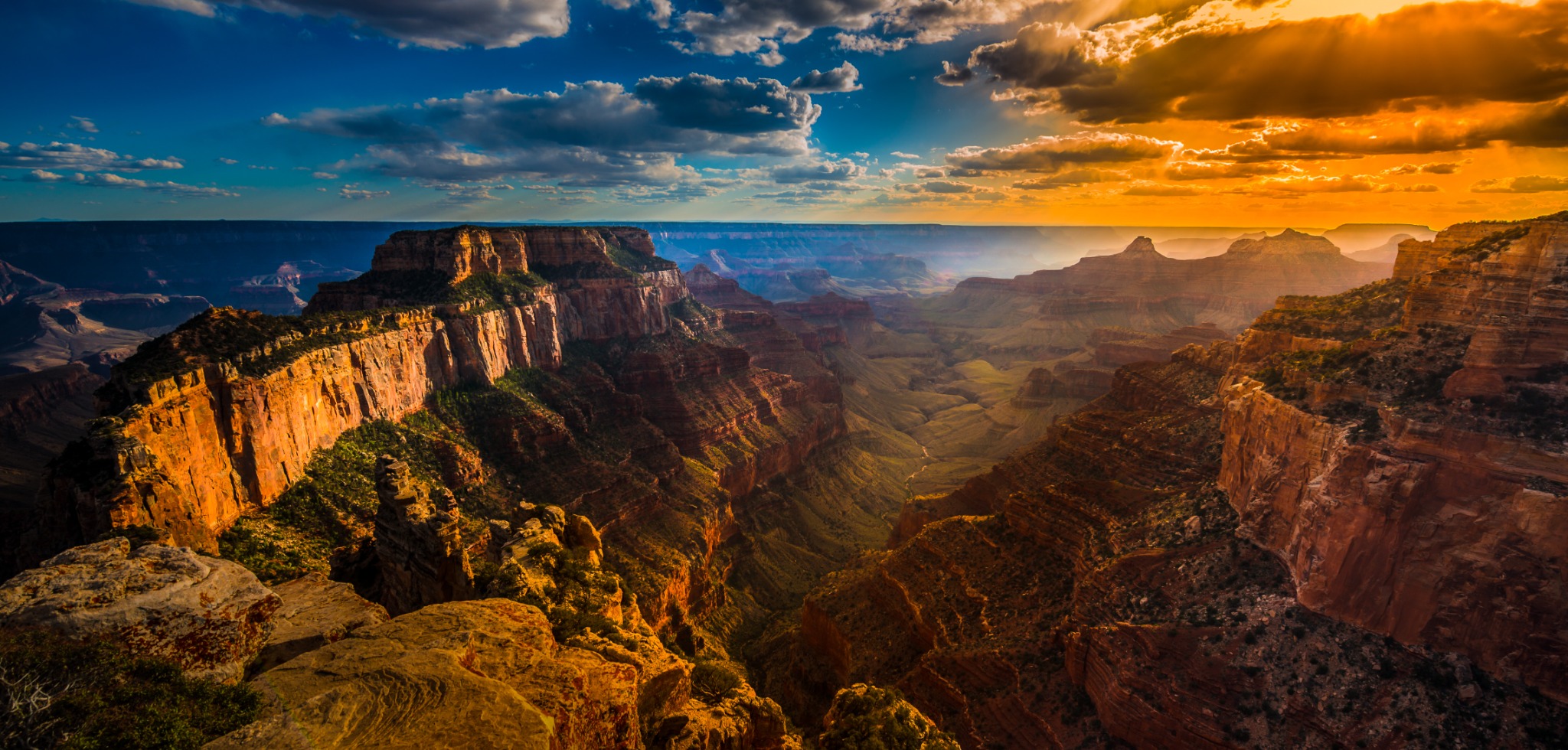 A panoramic view of the Grand Canyon illuminated by a vivid sunset.