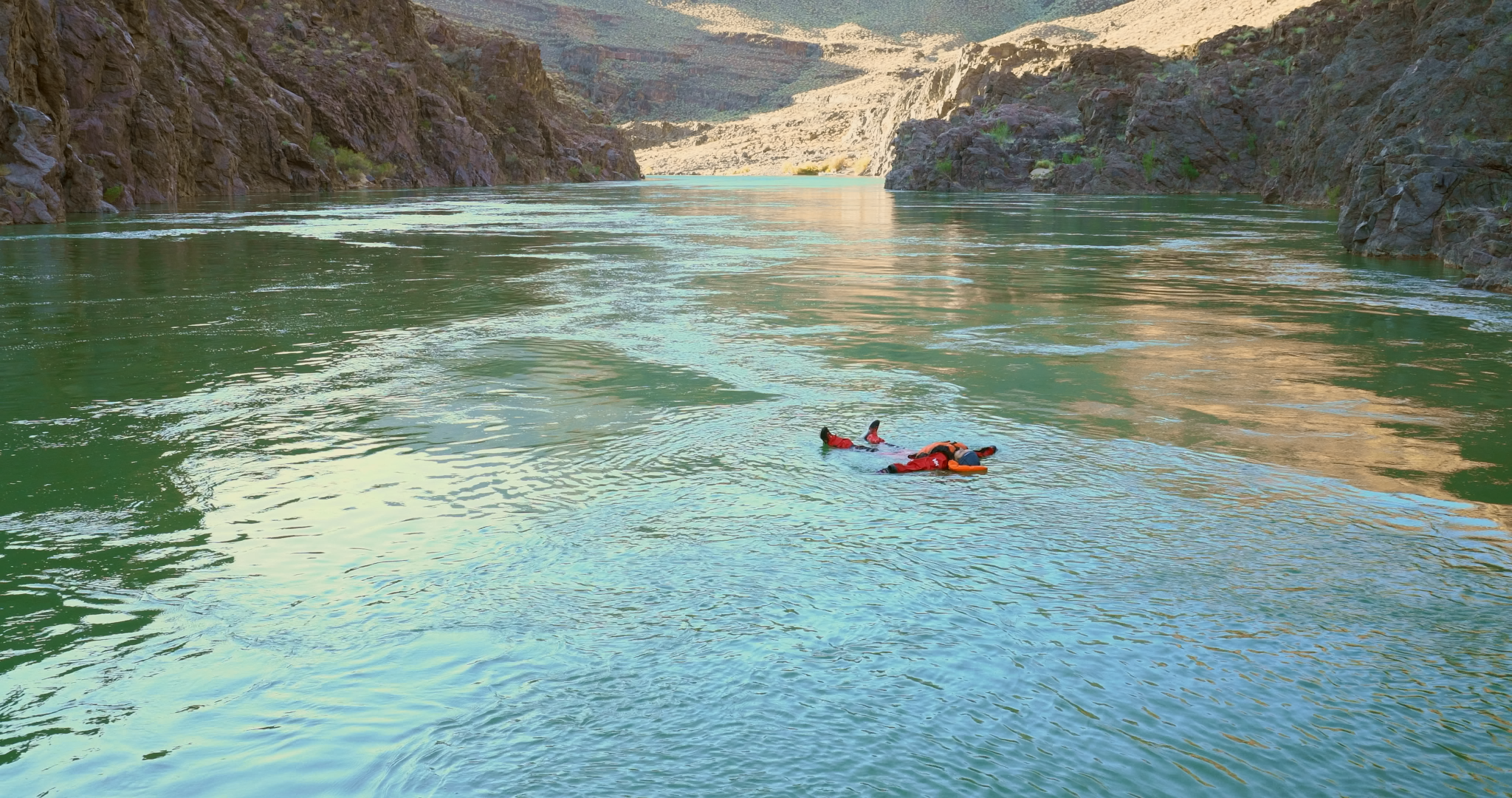 Two expedition participants floating together in the Colorado River, surrounded by the Grand Canyon.